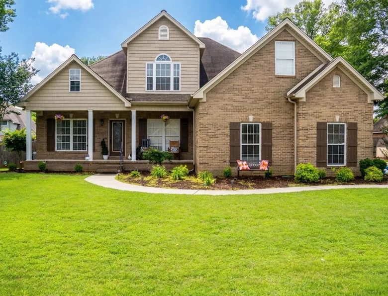 Brick and siding two story home with a covered front porch and a green lawn in the Shoals